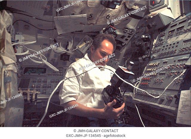 Cosmonaut Valery I. Tokarev, one of five mission specialists aboard Discovery, checks out a camera which is to be used later from this flight deck position to...