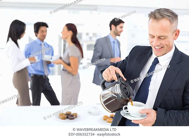 Businessman pouring himself some coffee in work