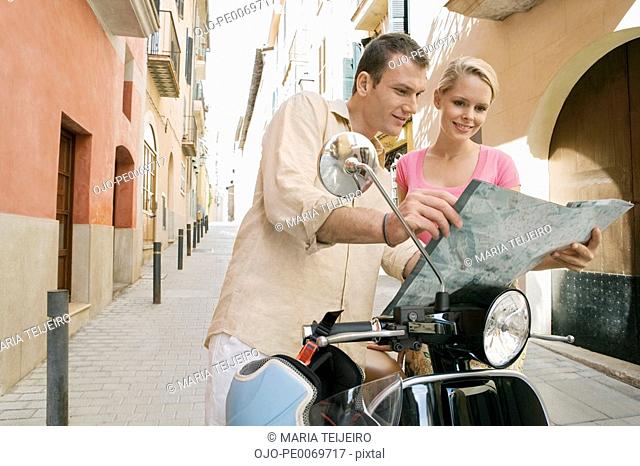Man and woman with scooter reading map