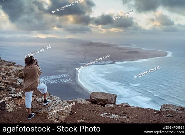 Tourist looking at Famara view while standing on mountain at Lanzarote, Spain