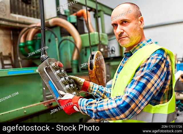 Arbeiter an Bedienfeld von Koordinatenbohrmaschine in Fabrik für Metallverarbeitung