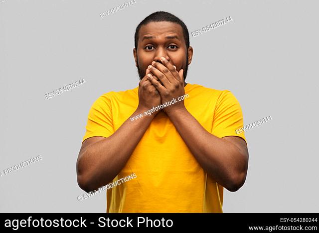 scared african american man covering his mouth
