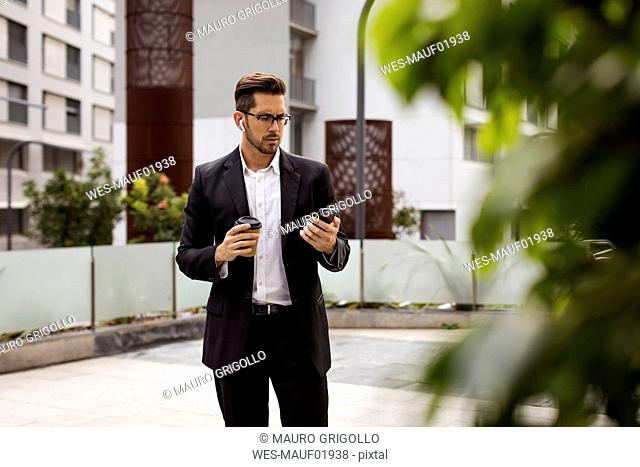 Businessman in the city checking cell phone