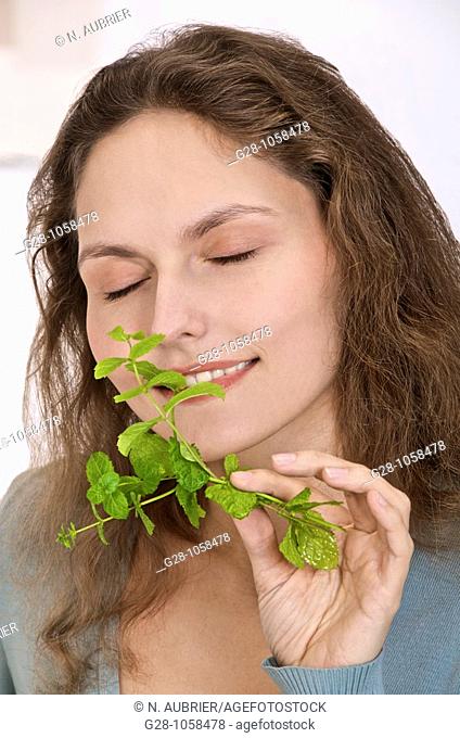young woman breathing a sprig of fresh mint