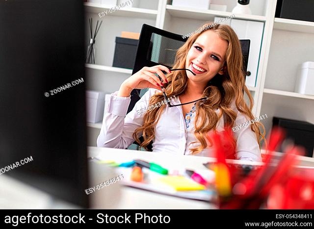 A young blond girl in a white blouse is working in the office. photo with depth of field