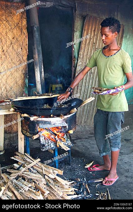AWASSA, ETHIOPIA - NOVEMBER 16, 2014: Young Boy frying fish on the market of Awassa on November 16, 2014 in Awassa, Great Rift Valley, Ethiopia, Africa