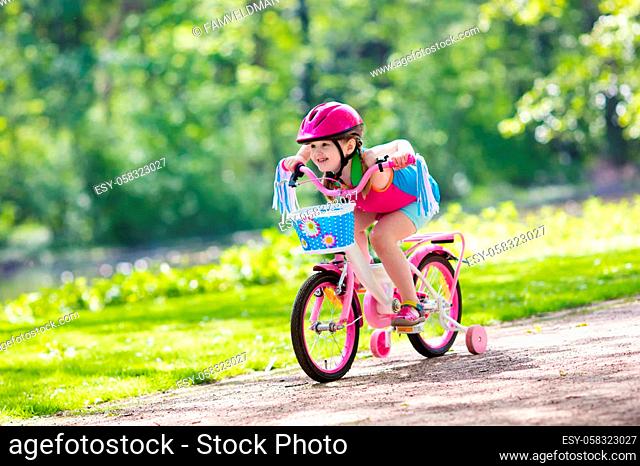 Child riding bike. Kid on bicycle in sunny park. Little girl enjoying bike ride on her way to school on warm summer day. Preschooler learning to balance on...