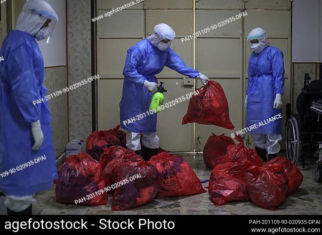 09 November 2020, Syria, Idlib City: Medical workers wearing personal protective equipment disinfect bags of medical waste at a hospital of the Syrian American...