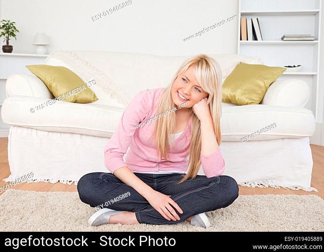 Attractive blonde woman posing while sitting on the floor