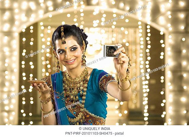 Woman holding an oil lamp and taking a picture of herself with a digital camera