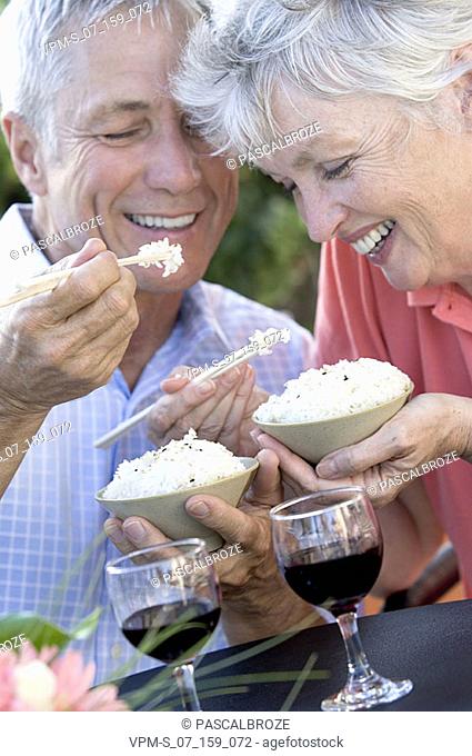 Close-up of a senior couple eating rice with chopsticks