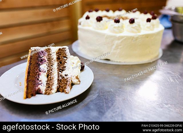 25 April 2021, Baden-Wuerttemberg, Todtnauberg: A piece of Black Forest cake lies on a plate next to a Black Forest cake in the run-up to a livestream of the...