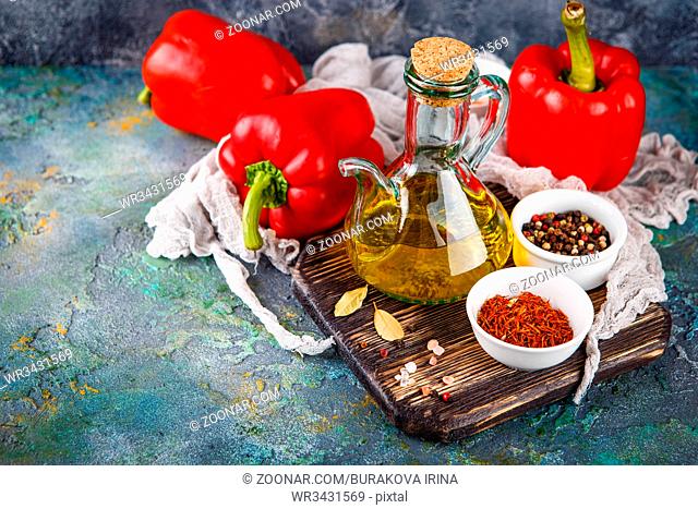 Fresh sweet red peppers, olive oil in bottle and cherry tomatoes on black concrete background