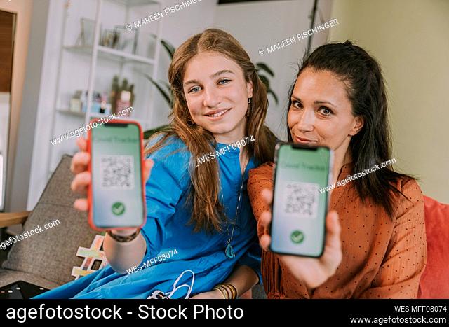 Smiling women showing COVID-19 tracker on smart phone at home