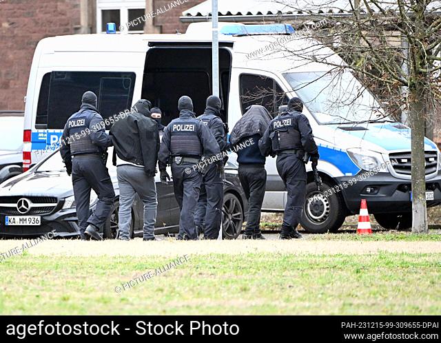 15 December 2023, Baden-Württemberg, Karlsruhe: Two people are led from a helicopter to a car by police officers at a helipad. On 14.12