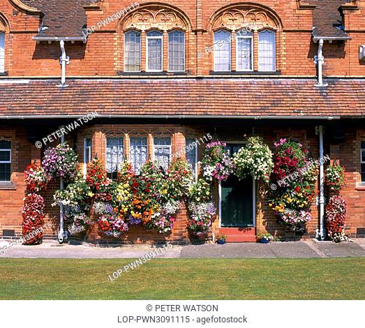 England, Merseyside, Port Sunlight. Flower baskets outside cottages in Port Sunlight. The houses were originally built for employees of Lever Brothers