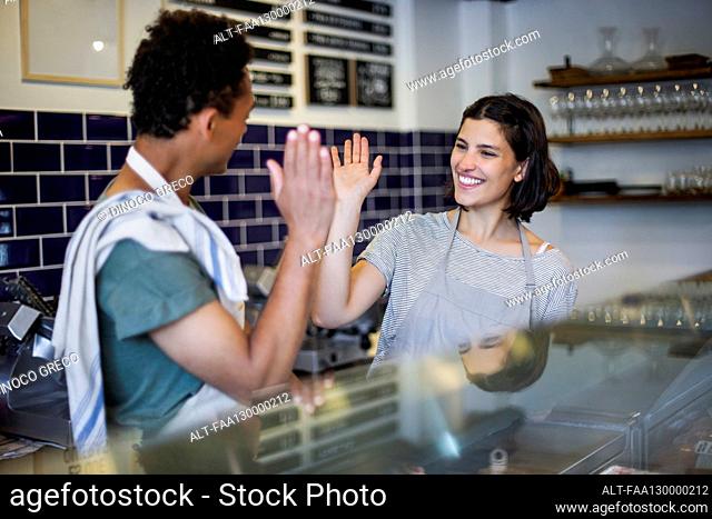 Grocery store female worker high fiving with male colleague