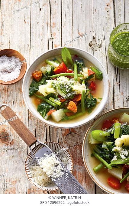 Colourful vegetable soup with pesto and parmesan