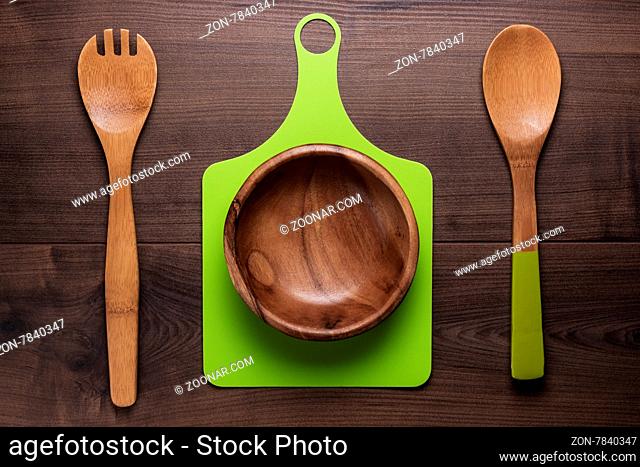 empty salad bowl and two spoons on wooden table