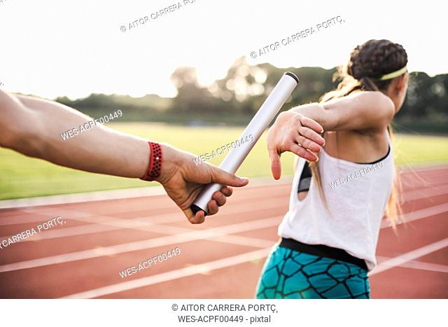 Close-up of a athlete passing the baton to a female athlete