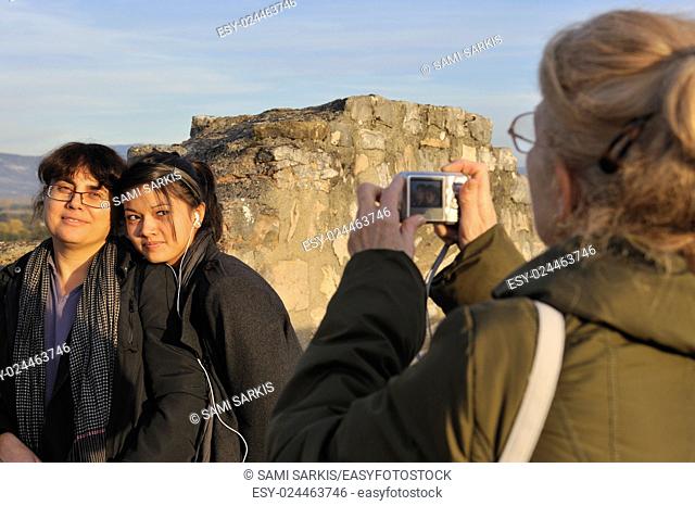 Grandmother taking photo of her granddaughter and daughter outdoors at a tourist destination
