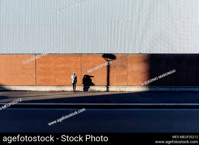 Young businesswoman in front of wall on sunny day