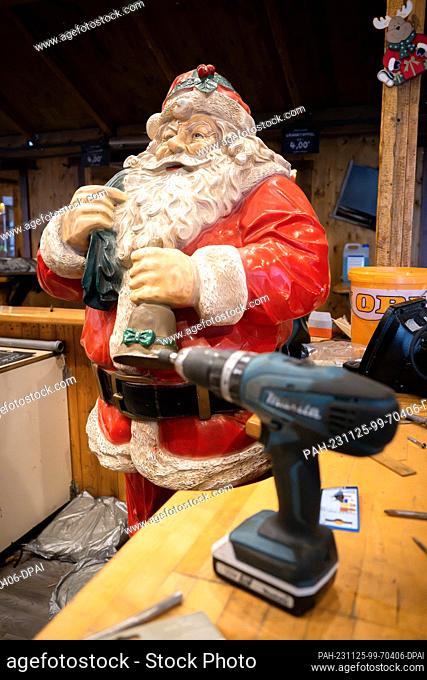 PRODUCTION - 22 November 2023, Bremen: A cordless screwdriver and a Santa Claus figure, taken while setting up a stall at the Christmas market