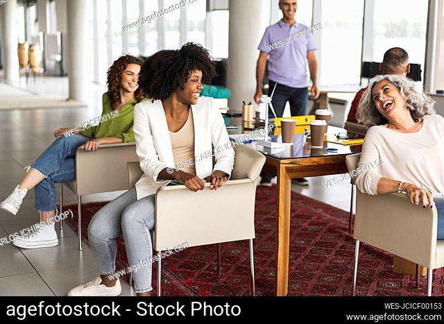 Happy business colleagues sitting on chairs at office