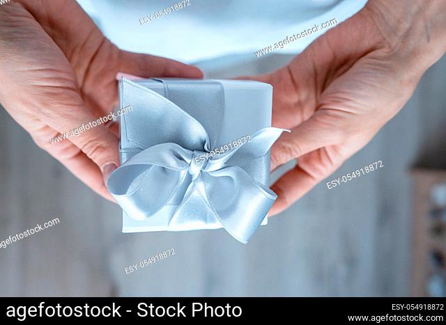 Woman hands holding Gift box, close-up. Wide angle format backdrop