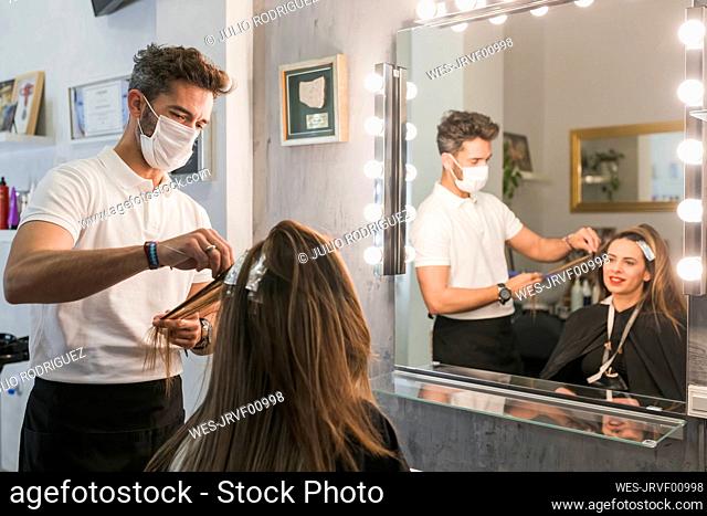Female customer getting hair dyed by male professional at salon during COVID-19