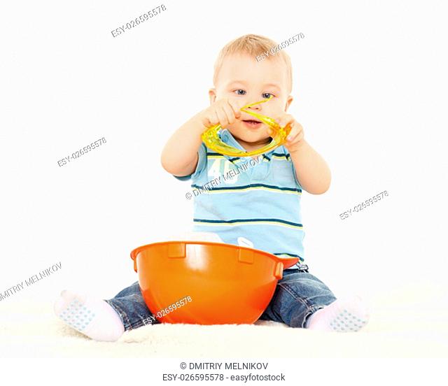Little child plays with orange construction protective helmet and huge yellow protective eyeglasses on a white background. Profession - future builder