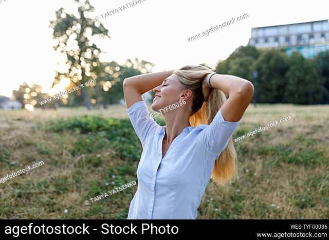 Smiling woman standing with hands in hair