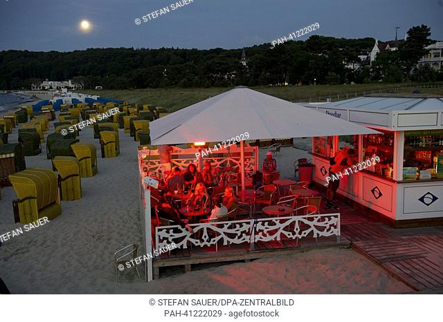 The full moon shines over the beach in Binz on Ruegen, Germany, 22 July 2013. Tourists sit in a beach bar and enjoy the summer evening