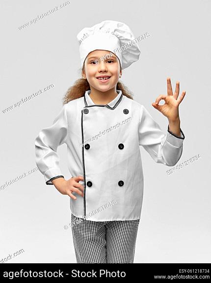 little girl in chef's toque showing ok gesture