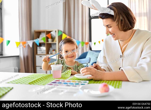 mother with child coloring easter eggs at home