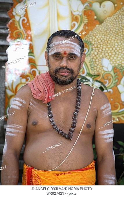 Religious preacher wearing rudraksha mala applying holy ash or bhasma with three bands on body standing outside Adi Shankaracharya temple ; Kaldi ; Kerala ;...