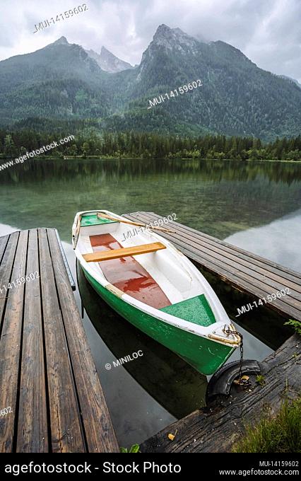 pleasure boat at pier on hintersee lake with reflection of watzmann mountain peaks. ramsau berchtesgaden bavaria, germany, europe