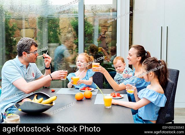Happy family eating fresh fruit breakfast in the kitchen