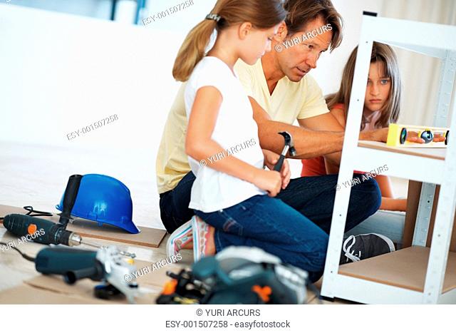 Man using a digital angle meter and showing the reading to his daughters
