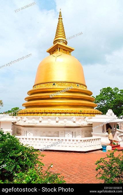 Golden buddhist dagoda or stupa monument with white fence on the front of Dambulla cave temple on Sri Lanka island