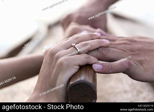 Hands of a wedding couple tying the scams on the bow of a boat in the Albufera de Valencia at the time the sun goes down, Spain