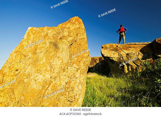 hiker on rocks near Roche Percee, Souris River Valley, Saskatchewan, Canada