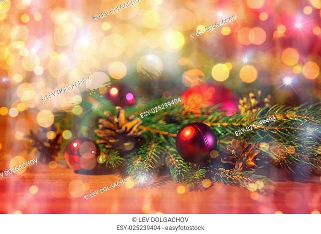christmas decoration, holidays, new year and decor concept - close up of natural fir branch, ball and pinecone over lights
