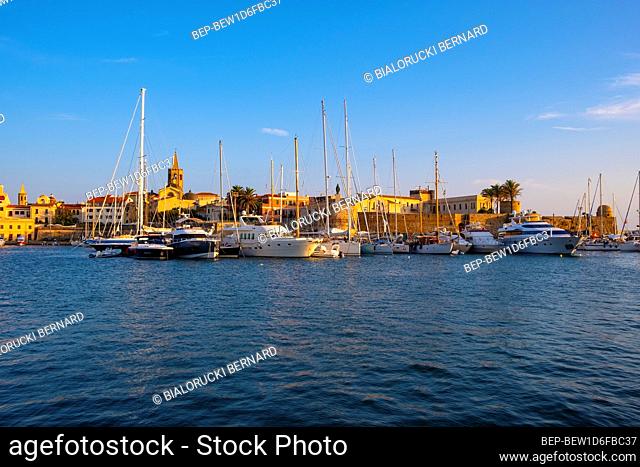 Alghero, Sardinia / Italy - 2018/08/10: Summer view of the Alghero Marina yacht port at the Gulf of Alghero at Mediterranean Sea with the Old Town quarter with...