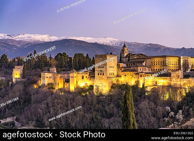View from Mirador de San Nicolas to the palace and fortress complex Alhambra and the snow-covered Sierra Nevada mountains at dusk, Granada, Andalusia, Spain