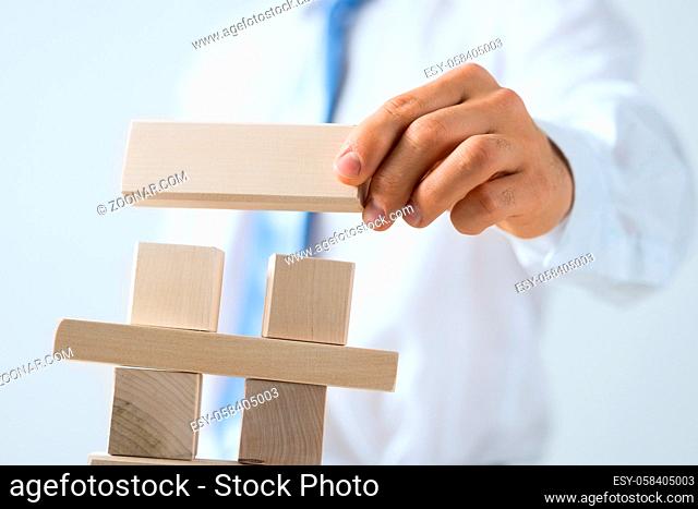 Close up of businessman building tower of wooden blocks