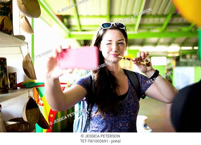 Caribbean Islands, Grenada, woman taking selfie with pipe in souvenir shop