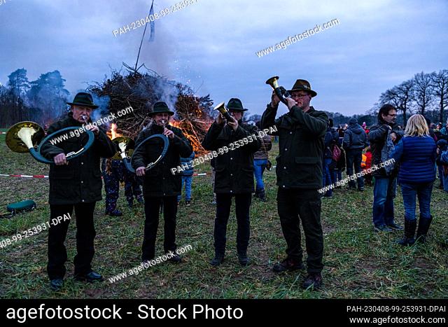 08 April 2023, Brandenburg, Cottbus: While the Easter fire is lit in Cottbus Branitz, brass horn blowers play a fanfare. The comrades of the volunteer fire...