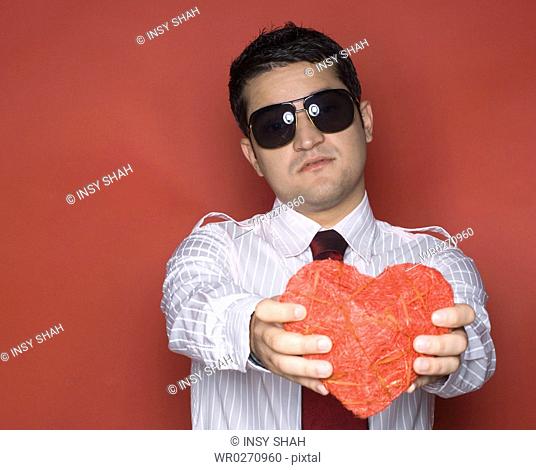 Portrait of a young man holding a heart shaped object