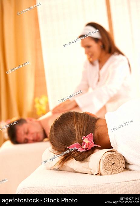 Conceptual image of getting massage in salon, flower in womans hair in focus